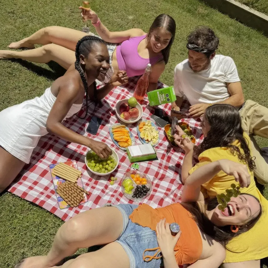 grupo de mujeres riendo y jugando mala leche de marihuana en picnic mas uvas verdes